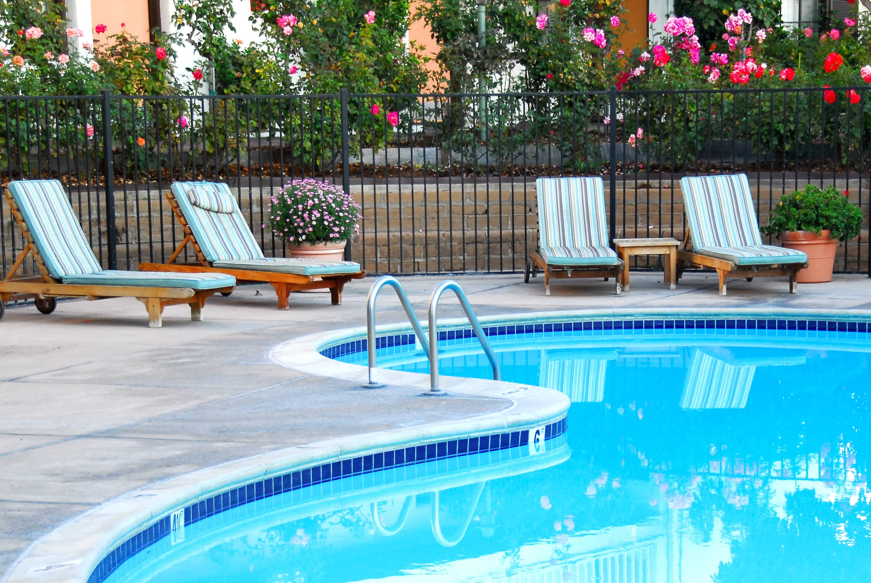 Beautiful,Swimming,Pool,Surrounded,By,Chairs,And,Flowers